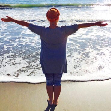 Woman arms open facing the ocean